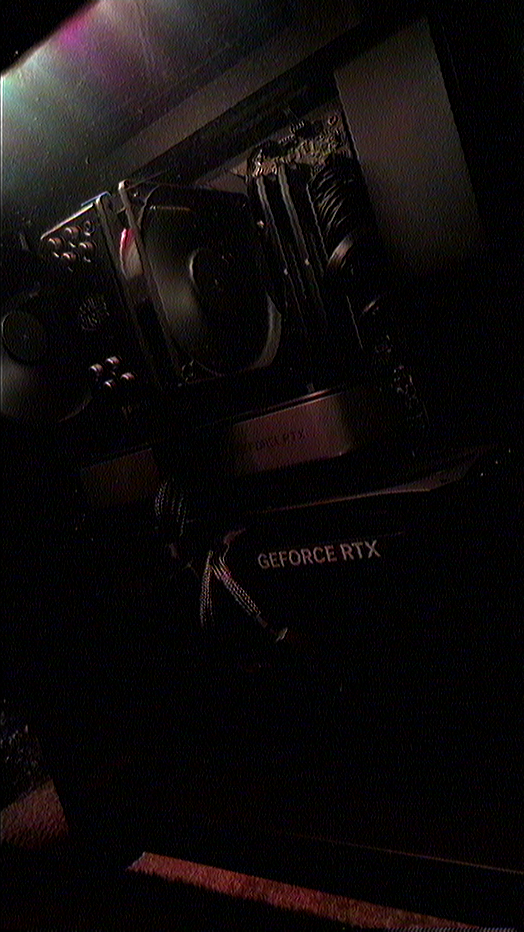 Angled interior view of an NZXT H7 Flow 2024 PC case showing a Cooler Master Hyper 212 (Black Edition) CPU cooler with fan, a mounted GeForce RTX 5070 Ti (SHADOW 3X OC) card with visible GEFORCE RTX text below a mounted RTX 3060 Ti (Founders Edition), braided power cables and nearby motherboard components; components are installed and powered inside a dim, moody workspace with low red and purple lighting conveying a focused, technical atmosphere.